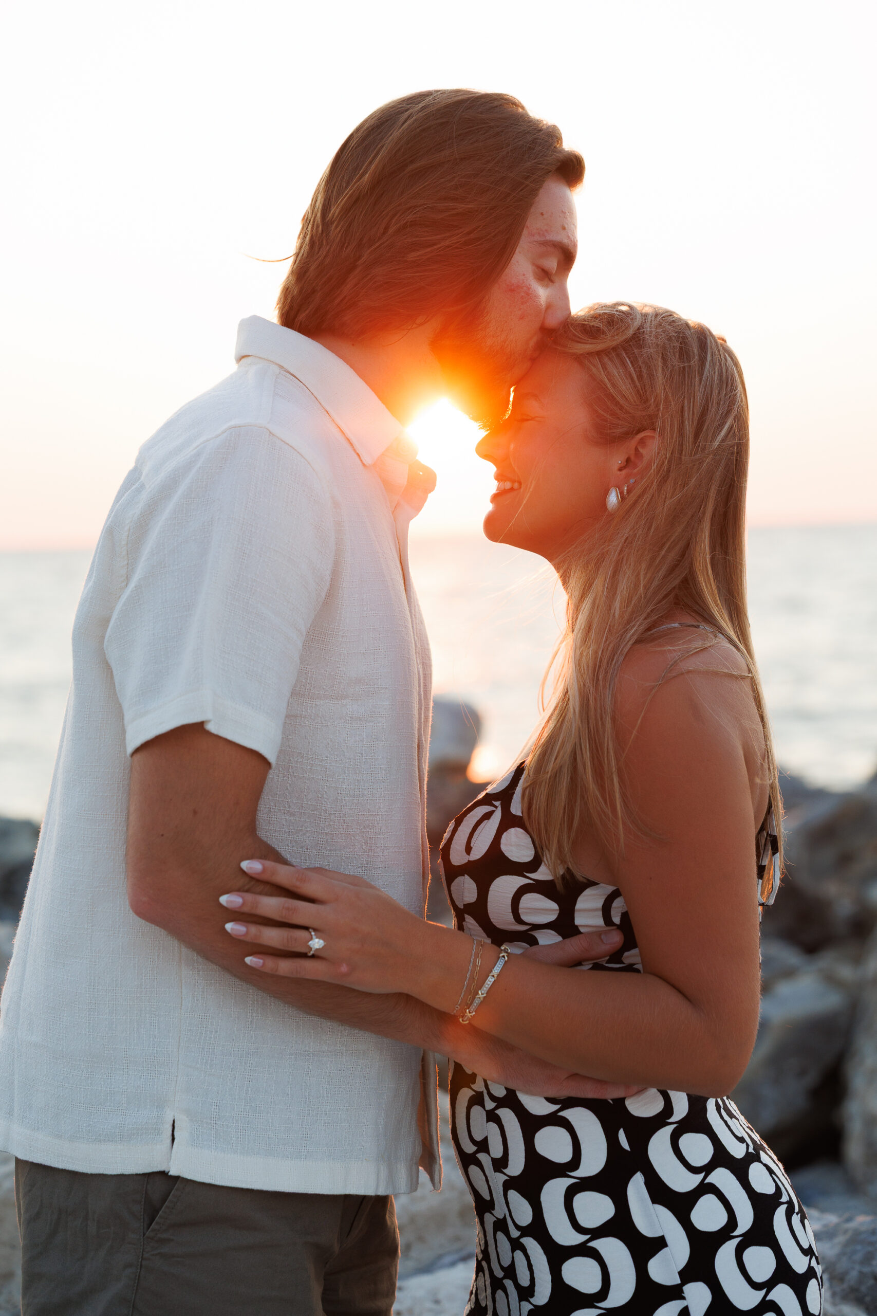 A couple joyfully holds an ultrasound image outdoors, celebrating their upcoming arrival, surrounded by greenery.